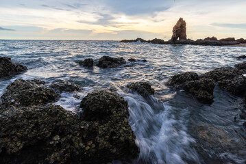 Boulders sticking out from smooth wavy sea. Tranquil scene.