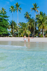 Obraz premium On a sunny day at Koh Kood Island beach, a women and men relax among palm trees and turquoise waters, seeking tranquility and joy in their tropical paradise, enjoying natures beauty of Thailand