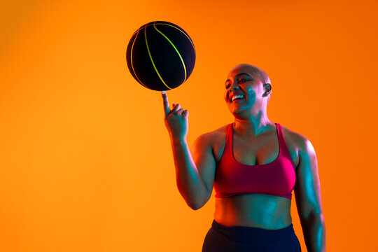 Athlete spinning a basketball on her finger in a studio