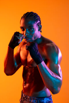 Athlete in sportswear posing in a boxing stance against an orange background
