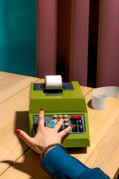 Hand using a vintage mechanical calculator in a colorful office setting