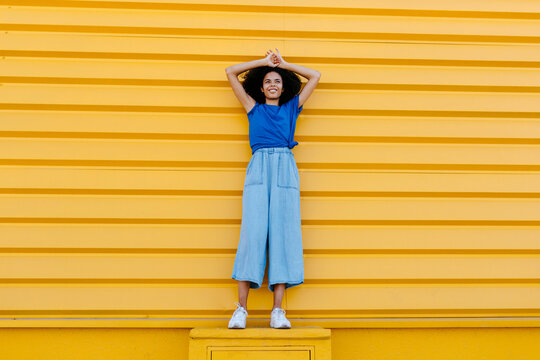 Smiling woman standing on platform in front of yellow wall