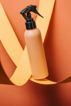 Spray bottle for body care with yellow and orange background
