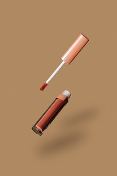 Floating brown lipstick tube and applicator on a beige background