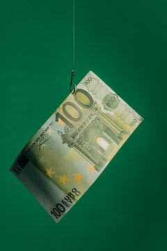 100 euro banknote on a hook against a green background symbolizing easy money and financial risk