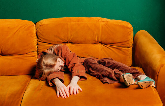 Woman dissolving into a sofa, expressing tiredness and depression indoors