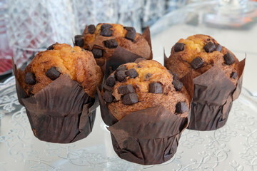 Four delectable, oversized chocolate chip muffins wrapped in parchment paper resting on a large...
