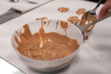 A child using a spoon to create a sweet dessert with milk chocolate and nuts. Ideal for family cooking, homemade treats, or kids' activities, food, dessert, and playful moments.
