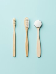 Three toothbrushes of different sizes and shapes on a light blue background. on the left, there is a wooden toothbrush with white bristles and a round handle.