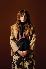 Handsome stylish man posing confidently in unique attire against a rich brown backdrop