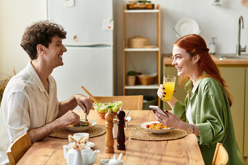 Young couple sharing joy and laughter during a relaxed meal at home with bright sunshine