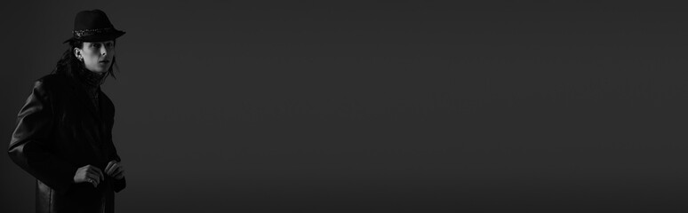 Stylish young man exudes confidence and charm in a sleek black outfit and hat