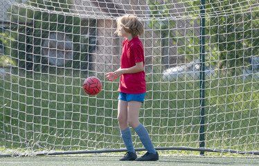 Obraz premium Girl Goalkeeper Stands At Goalposts During Children'S Football Match