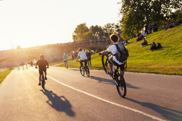 Scenic view youth people ride bicycles sunny Dresden Elbe riverside path against warm sunset glow...
