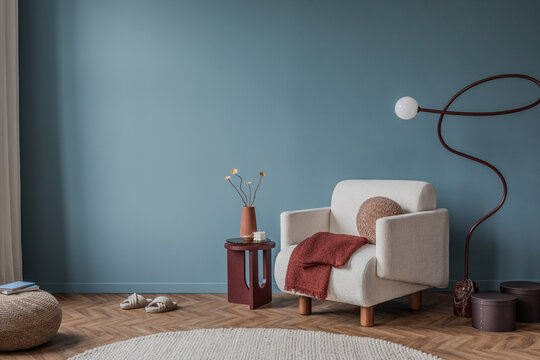 Cozy reading nook with cream armchair, terracotta accents, and sculptural floor lamp on blue wall.