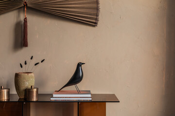 Minimalist console table decor with a black bird sculpture and rustic vase on a beige background.