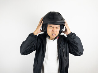 Young asian man holding his head with stressed and confused expression. While wearing a motorcycle helmet. Safety concept.