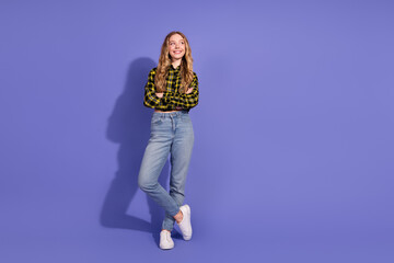 Cheerful young woman in casual outfit standing confidently against a vibrant purple backdrop with a...