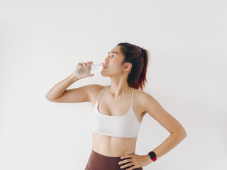 Happy asian Thai woman holding water bottle and drinking between resting workout, wear white sport...