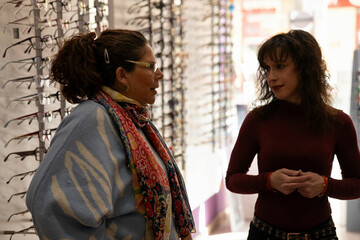 Optician advising customer choosing eyeglasses in optical store