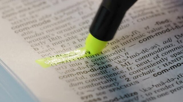 Commodify Business Dictionary Highlighter Concept, highlighting a word in a dictionary to show it's definition