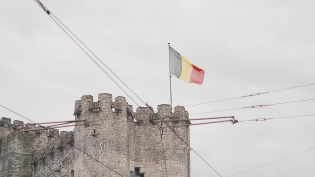 Bandiera Belga che svetta su una torre , ripresa dal basso, durante una giornata nuvolosa. Citt&agrave; Europea