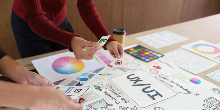 Interactive Design Elements in UX/UI. A group collaborates around design materials, examining various design components.