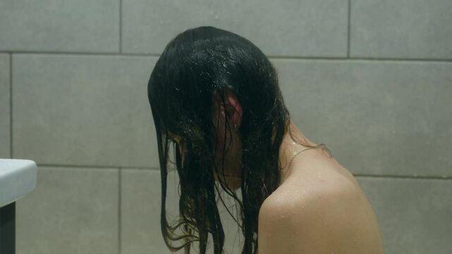 Depressed female experiencing overwhelming mental health challenges, sitting dejectedly in shower with wet hair obscuring face, embodying deep emotional distress and psychological vulnerability