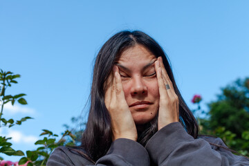 Woman suffering from seasonal allergies, holding a tissue to her nose. Hay fever, pollen allergy,...