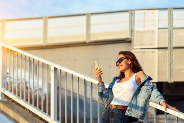 Smiling urban woman standing on city stairway checking smartphone