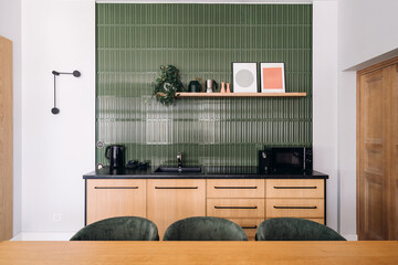 Modern kitchen design with green tiles and wooden elements in urban apartment