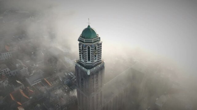 Zwolle Peperbus church tower rising up over the fog in the downtown district aerial drone view during an autumn sunrise.