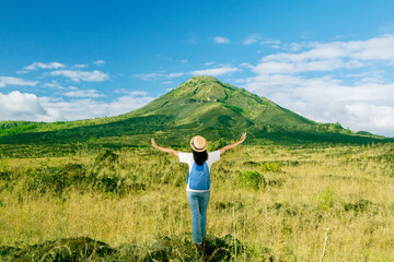 Female Traveler Enjoying Nature with Open Arms in Front of a Majestic Volcano