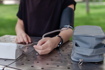 Fototapeta premium Young boy measuring blood pressure in a park. Concept of children’s health, early diagnosis, and medical awareness. Preventive healthcare and active lifestyle