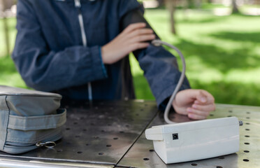 
Young boy measuring blood pressure in a park. Concept of children’s health, early diagnosis, and medical awareness. Preventive healthcare and active lifestyle