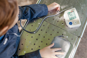 
Young boy measuring blood pressure in a park. Concept of children’s health, early diagnosis, and...