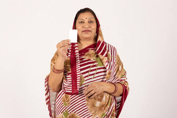 Indian senior rural woman showing Aadhar card on white studio background