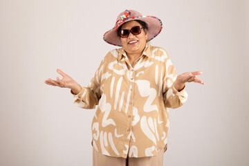 Styling senior woman. Indian happy attractive senior woman open hands while wearing hat on grey studio background