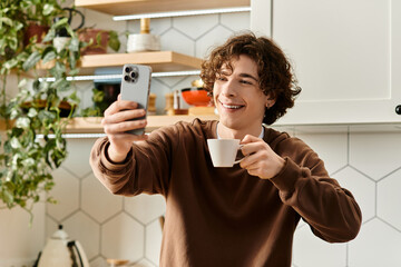 Curly student enjoying a warm drink while capturing a moment in his cozy apartment