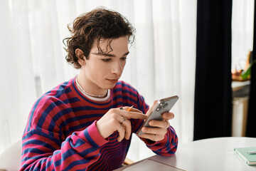 Curly non-binary student in vibrant sweatshirt uses smartphone in stylish apartment