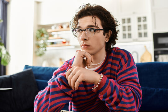 Curly-haired non binary person reflects on life in a stylish modern apartment
