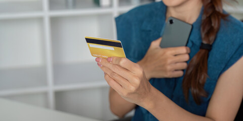 Credit Card and Mobile Banking. A person holding a credit card and smartphone while managing...