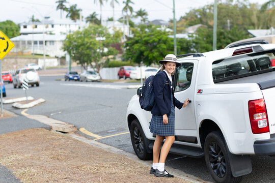 Schoolgirl in uniform about to open car door in street