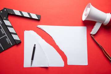 Torn documents, movie clapper board, megaphone.