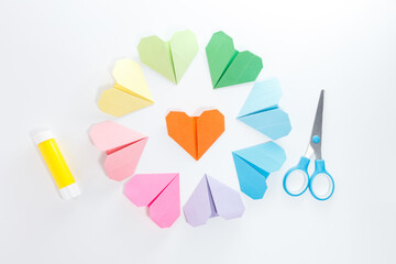 Colorful origami hearts arranged in a circle on pastel background with scissors and glue. Flat lay composition with craft supplies. Perfect for DIY projects, school activities, and stationery branding
