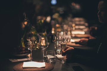 A person sits at a table with wine glasses and a napkin