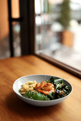 Bowl with quinoa, shrimp, avocado, greens, arugula and cucumber on the table, top and side view