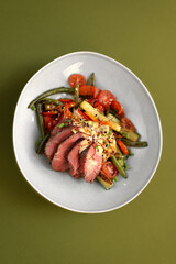 Hot salad with veal, zucchini, tomatoes, asparagus and cheese