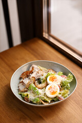Classic Caesar salad with eggs, chicken, cheese, green lettuce, sprinkled with cheese