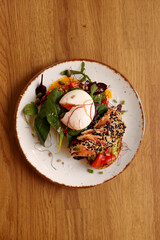 Toasted bread sandwich with guacamole, red fish, egg and greens on a plate on a brown table